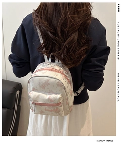 Detailed view of white mini backpack with pink butterfly prints and front pocket detail