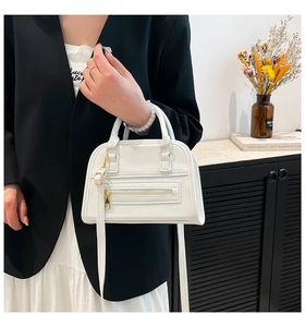 Detail of white litchi pattern leather handbag with gold zipper and dual handles