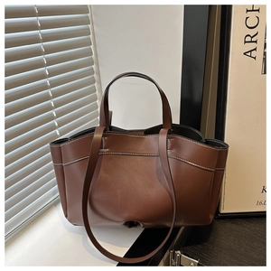 Detailed view of dark brown leather tote bag with white stitching and shoulder straps