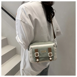 Close-up of contrast canvas messenger bag with brown straps and cute rabbit label