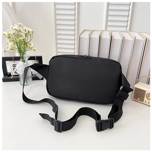 Sac bandoulière minimaliste en nylon noir avec sangle réglable sur une étagère