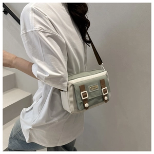 Detail of color-block canvas crossbody bag with adjustable strap and decorative buckles