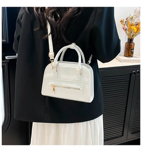 Detail showing white lychee texture leather bag with gold zipper and adjustable strap