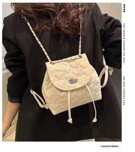 Detail of heart quilted cream backpack featuring chain straps and silver twist lock