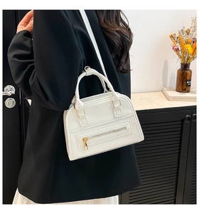 Close-up of white lychee pattern leather Boston bag with elegant gold zipper details