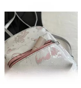 Close-up of white leather backpack with pink butterfly prints and front zipper pocket
