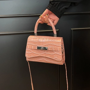 Pink crocodile pattern handbag with silver swivel lock shown on a black background