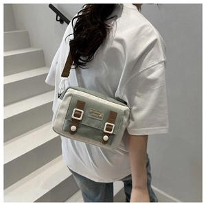Detail of canvas crossbody bag with contrast color design and adjustable strap on a model