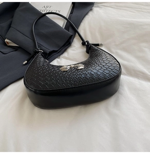 Detail of black crescent hobo bag with crocodile texture and silver bow ornament