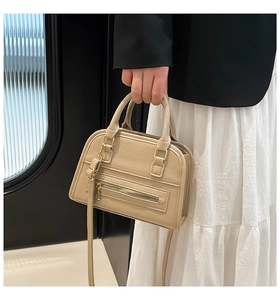 Close-up of stylish khaki tote bag with lychee texture held by a model in casual attire