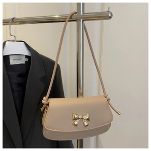 Détail du sac beige avec nœud doré élégant et bandoulière fine en similicuir
