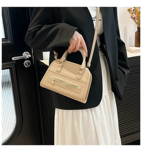 Detail view of khaki leather handbag with front zipper and adjustable shoulder strap