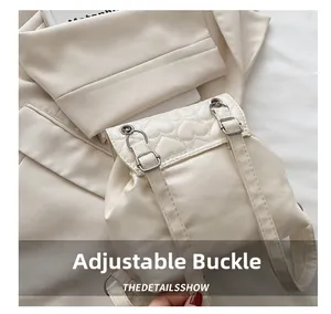 Detail view of cream backpack featuring heart quilting and adjustable metal buckle