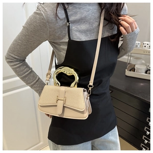 Detail of beige shoulder bag with H-shaped buckle and gold irregular metallic handle