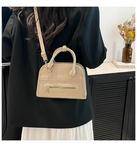 Detailed view of beige pebble leather handbag worn over the shoulder by a model