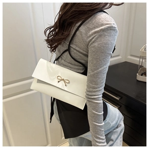 White faux leather envelope crossbody bag with a gold metal bow and thin chain strap