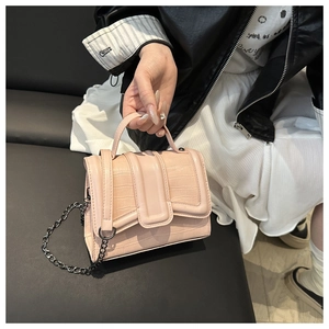 Sac à main rose en cuir PU effet crocodile avec bandoulière chaîne tenu par un mannequin