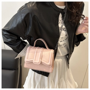 Détail du sac à main rose gaufré crocodile avec bandoulière chaîne porté par un mannequin