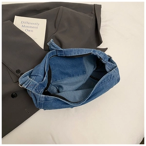 Interior detail of a large denim tote bag showing the inner pocket and zip closure