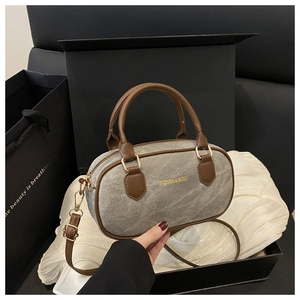 Detail of grey denim mini bag with brown leather handles on white satin in a gift box