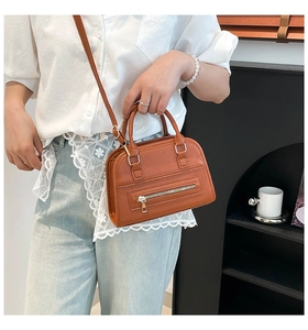 Detail of a brown lychee pattern handbag featuring a front zipper and gold-tone hardware