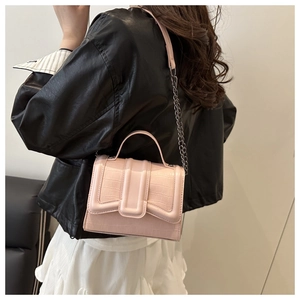 Sac à main rose à motif crocodile avec bandoulière chaîne porté par un mannequin