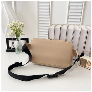 Détail du sac bandoulière en nylon kaki avec sangle réglable sur une surface blanche