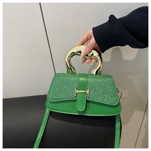 Detail of green sequined handbag with sculptural gold metal handle and polished lock