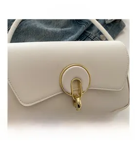 Detail of white leather-like handbag with gold metal buckle on denim background