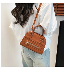 Model view showing the back side of a caramel brown litchi leather Boston bag on shoulder