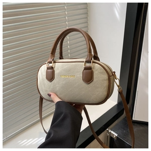 Detail of beige canvas bowling bag with brown leather handles and gold fashion lettering