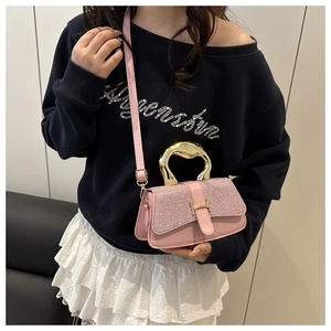 Close-up of pink glitter flap bag featuring golden H-shaped clasp and metal handle