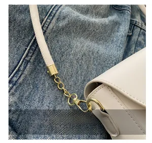 Detailed macro of golden metal lobster clasp and white leather strap stitching