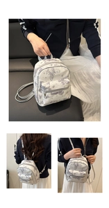 Detail of white leather backpack with purple butterfly prints and silver metal zippers
