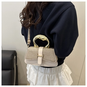 Detail of a chic cream mini bag featuring a gold curved metal handle and H-shaped clasp