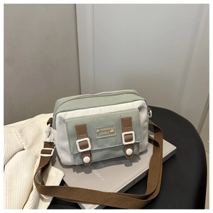 Detail van lichtgroene canvas crossbodytas met leren riem in een rustige setting