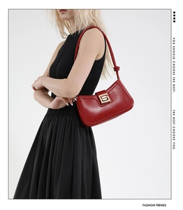 Detail of red leather shoulder bag with gold square buckle and stylish knotted strap