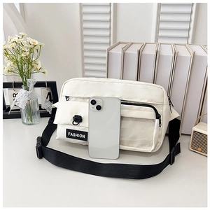 White canvas crossbody bag with adjustable strap and fashion label shown with smartphone