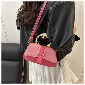 Detail of rose pink crossbody box bag with gold metal handle and H buckle on a model