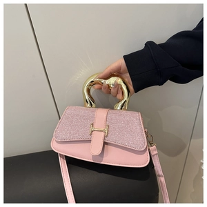 Detail view of pink glitter shoulder bag with golden H-shaped buckle and metal handle