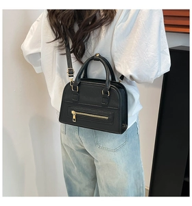 Close-up of black pebbled leather tote bag showing golden hardware and upper body scale