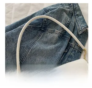 Detail showing comfortable thick white leather handle and gold metal hardware on bag