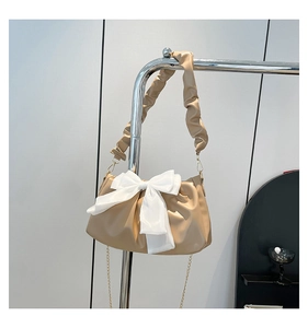 Detail of a beige PU leather shoulder bag featuring a large silk bow and pleated strap