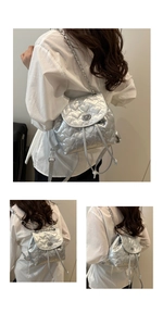 Detail of silver heart-quilted backpack with metallic texture and chain strap