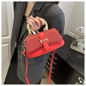 Detail of red glitter flap handbag with golden U-shaped metal handle and buckle