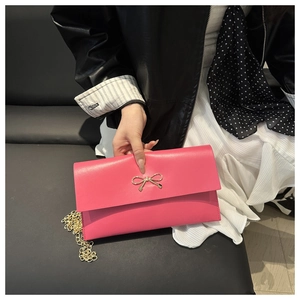 Detailed close-up of a pink crossbody bag featuring a delicate gold bow metal buckle clasp