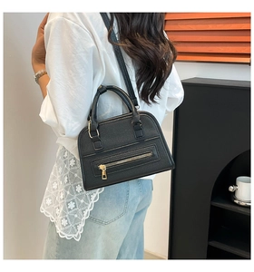 Detail of black pebbled leather tote bag with gold hardware worn by model as a shoulder bag