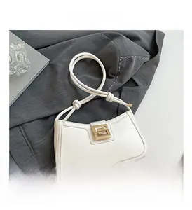 Close-up of white leather half-moon bag with gold G-buckle and knotted rope strap