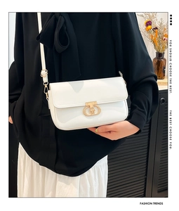 Detail of interlocking gold metal clasp on creamy white leather crossbody bag