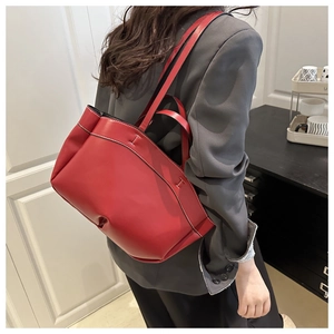 Red leather tote bag with H hardware worn by a model in a casual indoor setting
